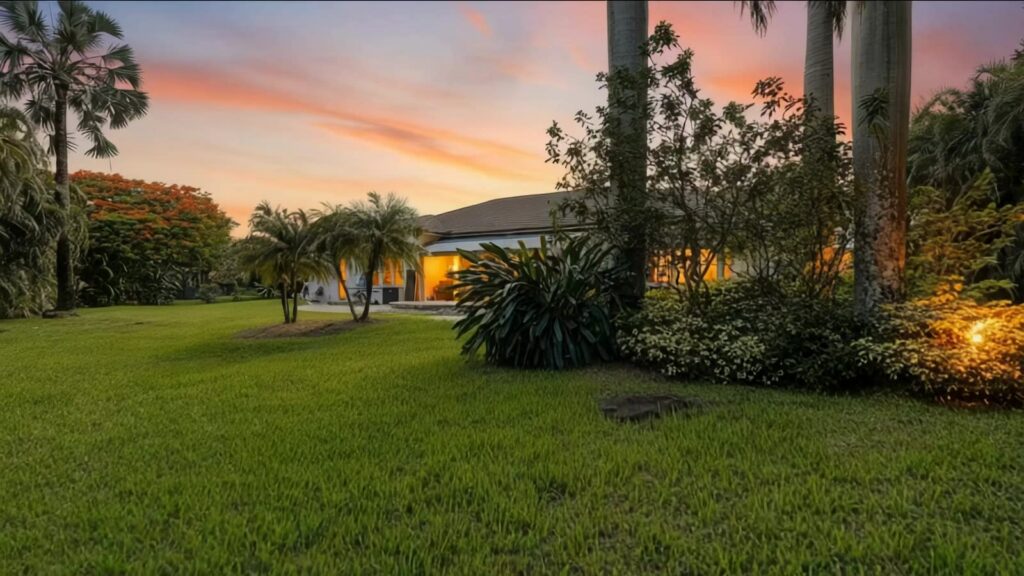 Wide front lawn and mature palms at twilight on a gated 1.2 acre Davie homesite