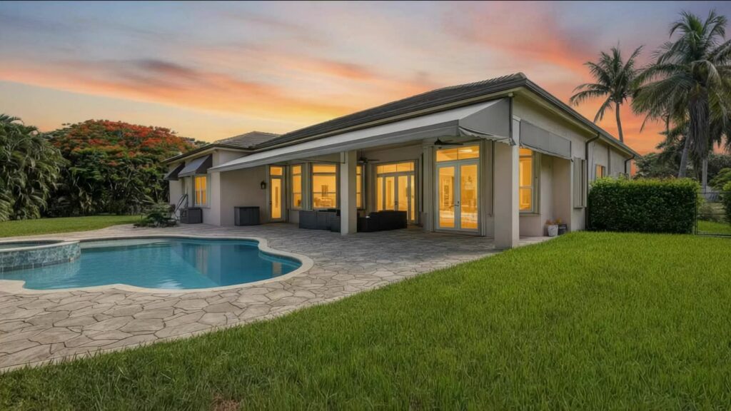 Rear elevation with covered patio and salt water pool lit at sunset