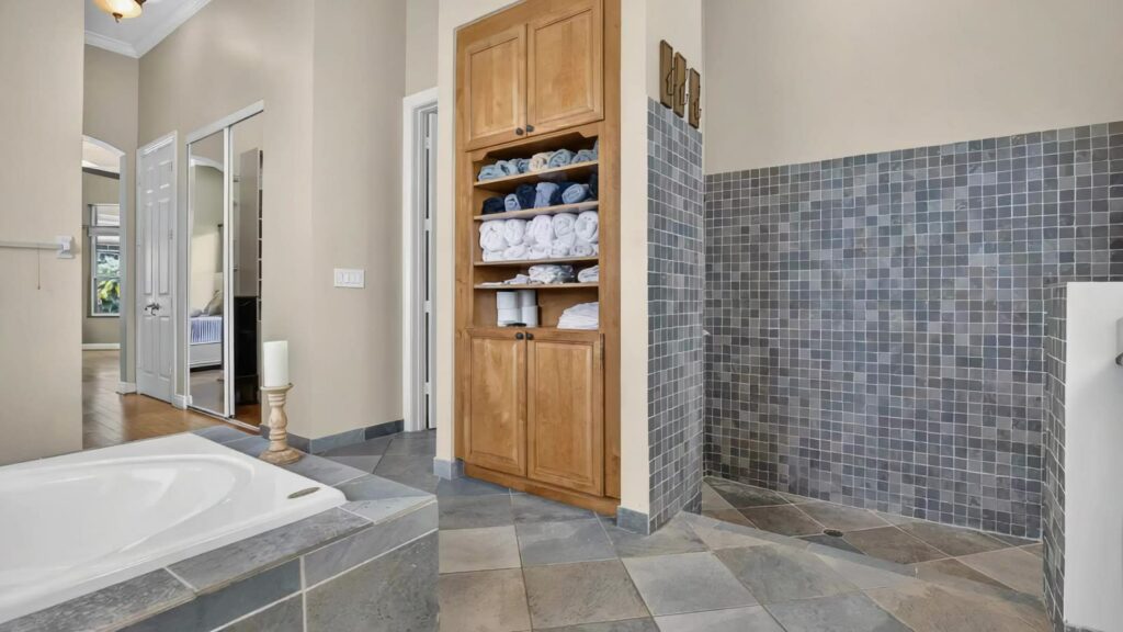 Separate walk in shower with mosaic tile and built in linen storage