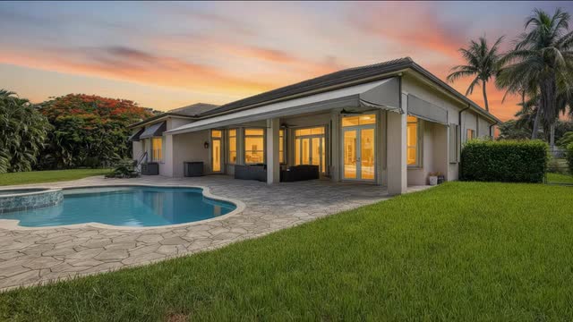 Rear elevation with covered patio and salt water pool lit at sunset