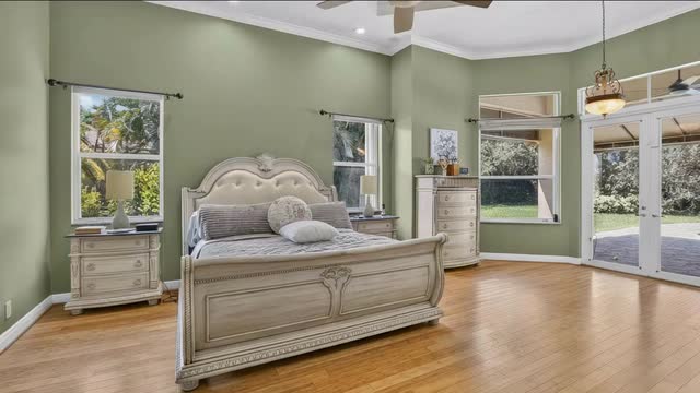 Ground floor primary bedroom with hardwood floors, bay window and French doors to the patio